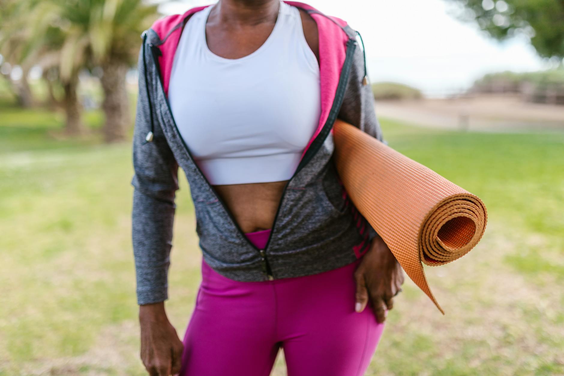 Smiling woman stretching gently on a yoga mat outdoors.